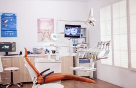 Dental chair and other accesorries used by dentist Dental chair and other accesorries used by dentist in empty cabinet. Stomatology cabinet with nobody in it and orange equipment for oral treatment.